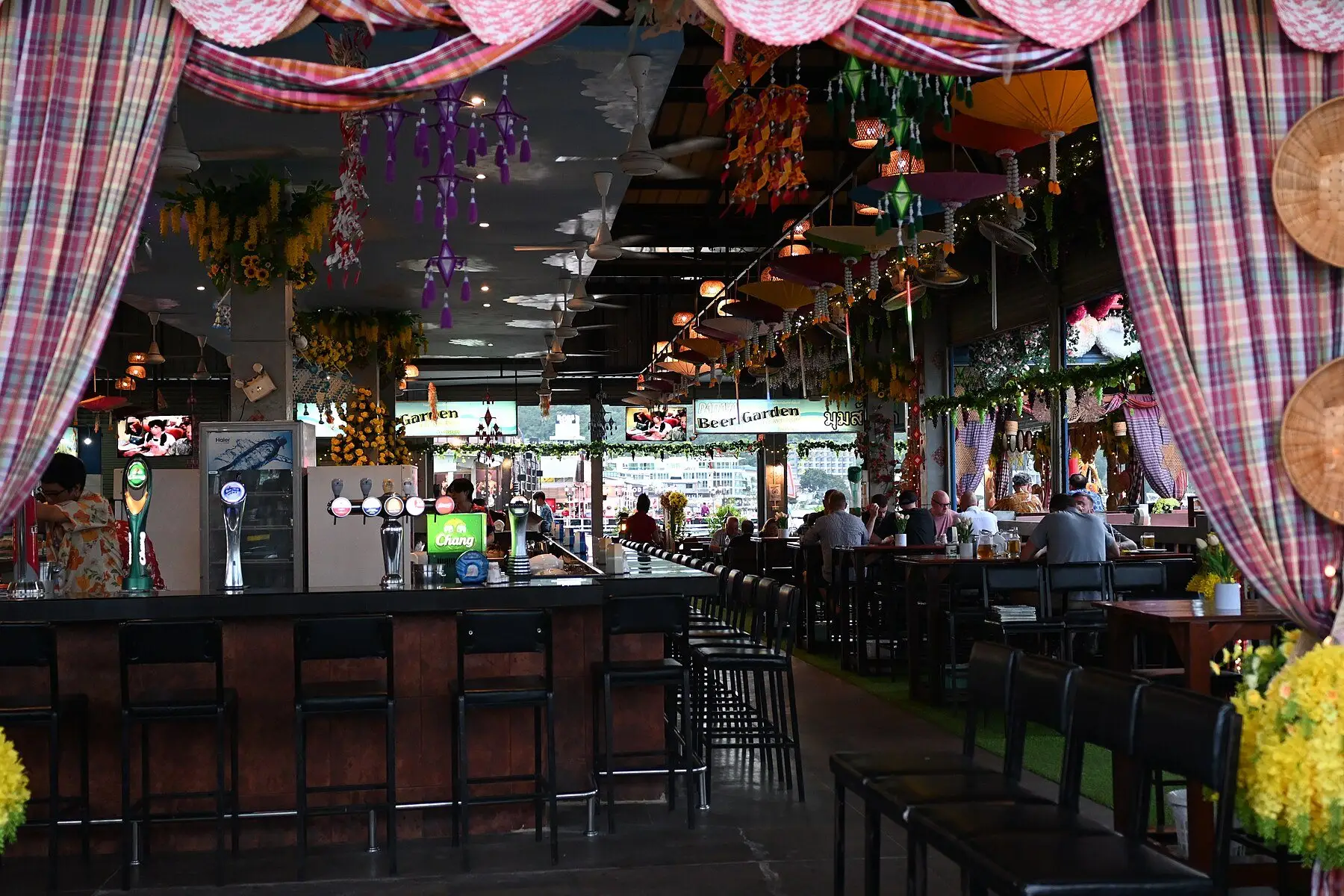 A covered outdoor bar counter lined with high stools