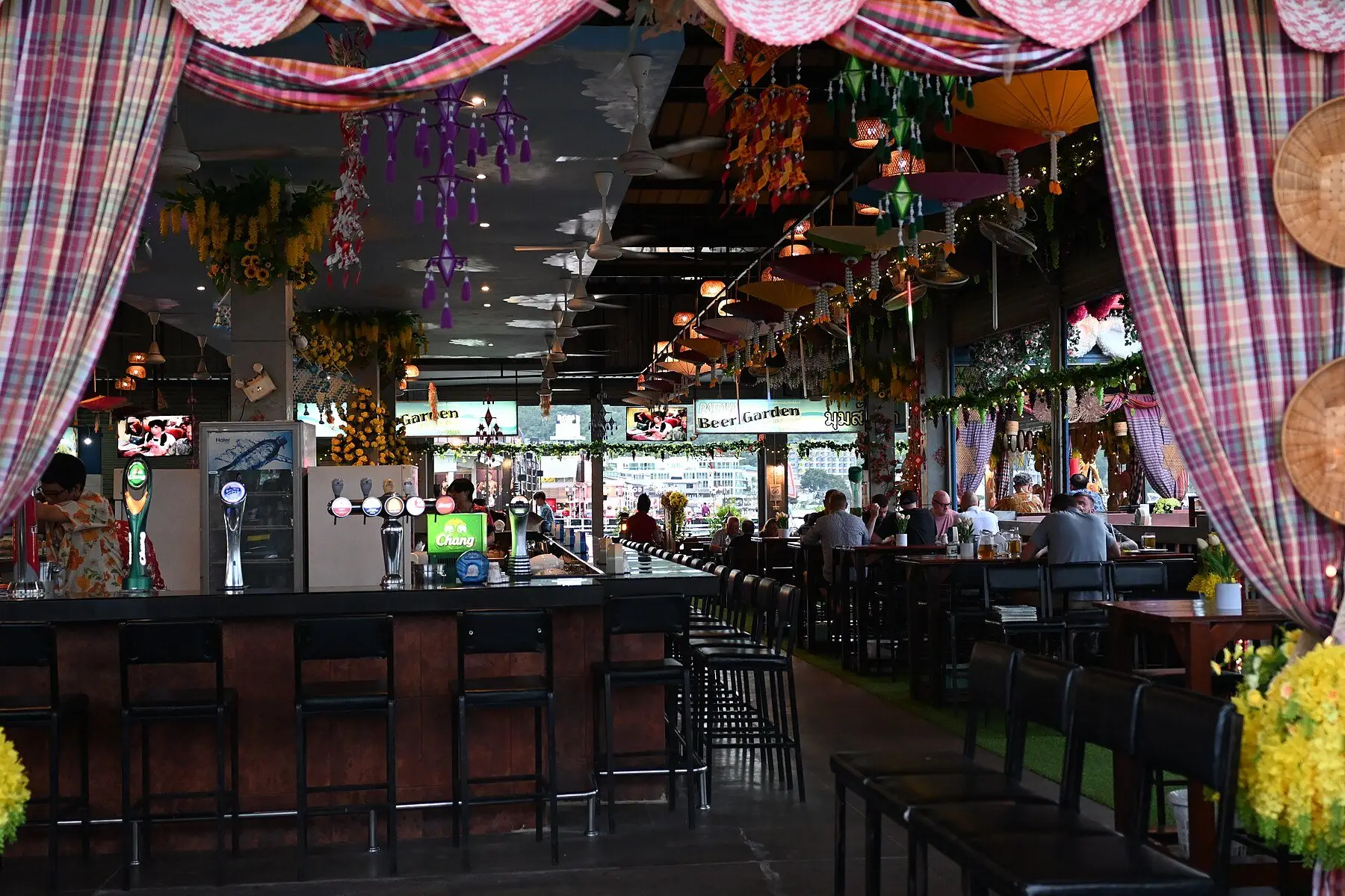 A covered outdoor bar counter lined with high stools