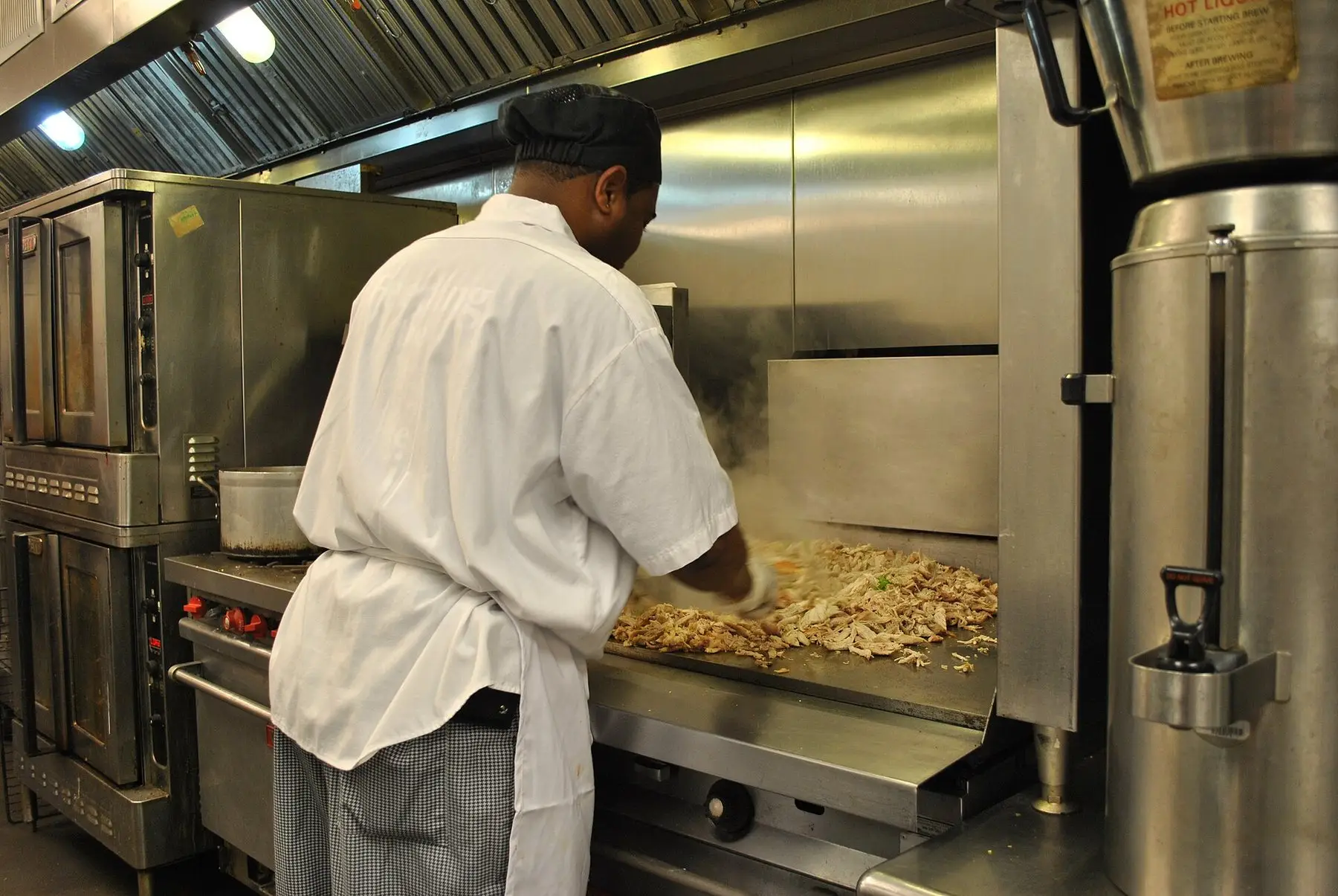 A cook working food across a solid flat-top griddle