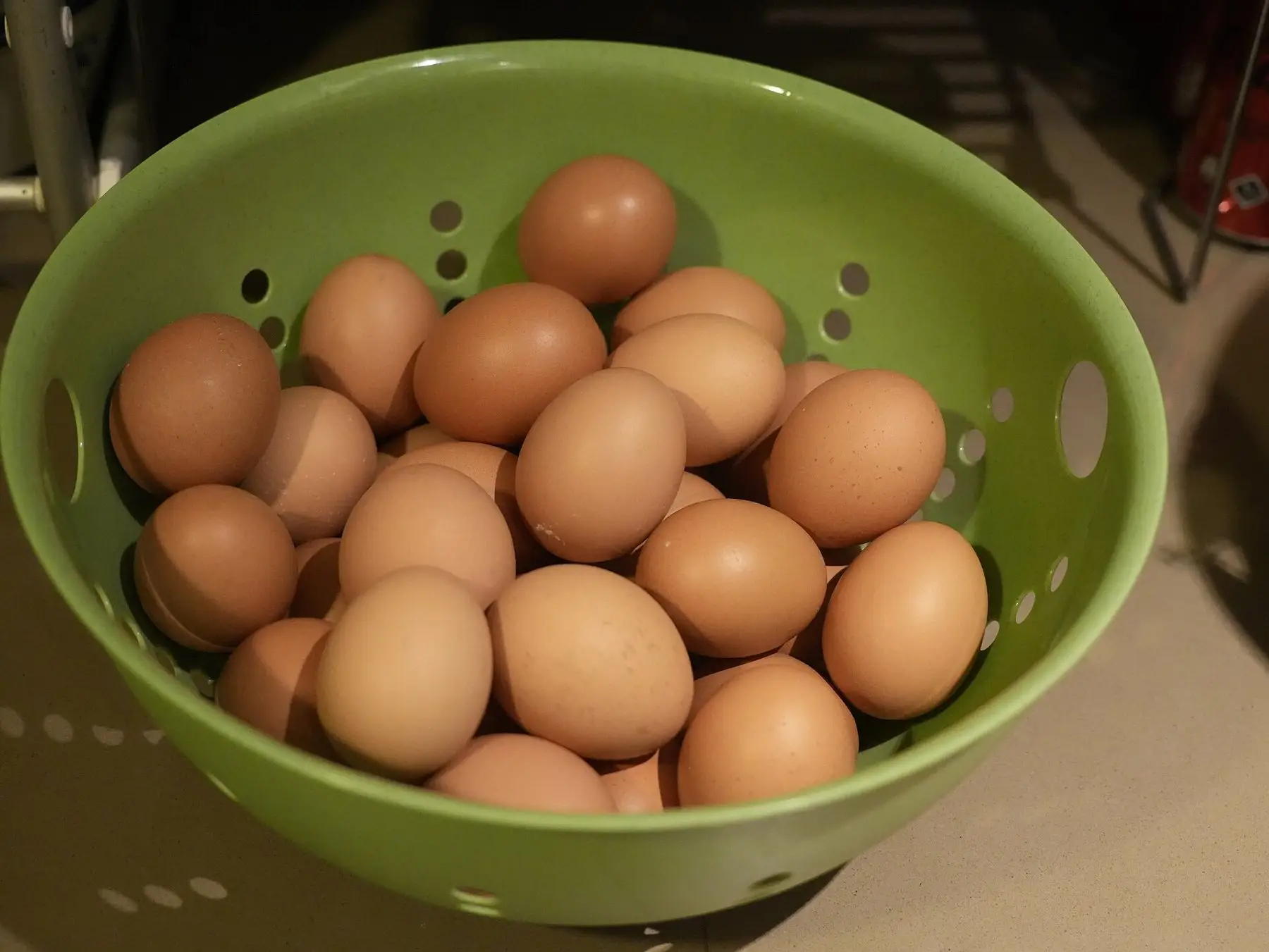 Brown chicken eggs collected in a green colander