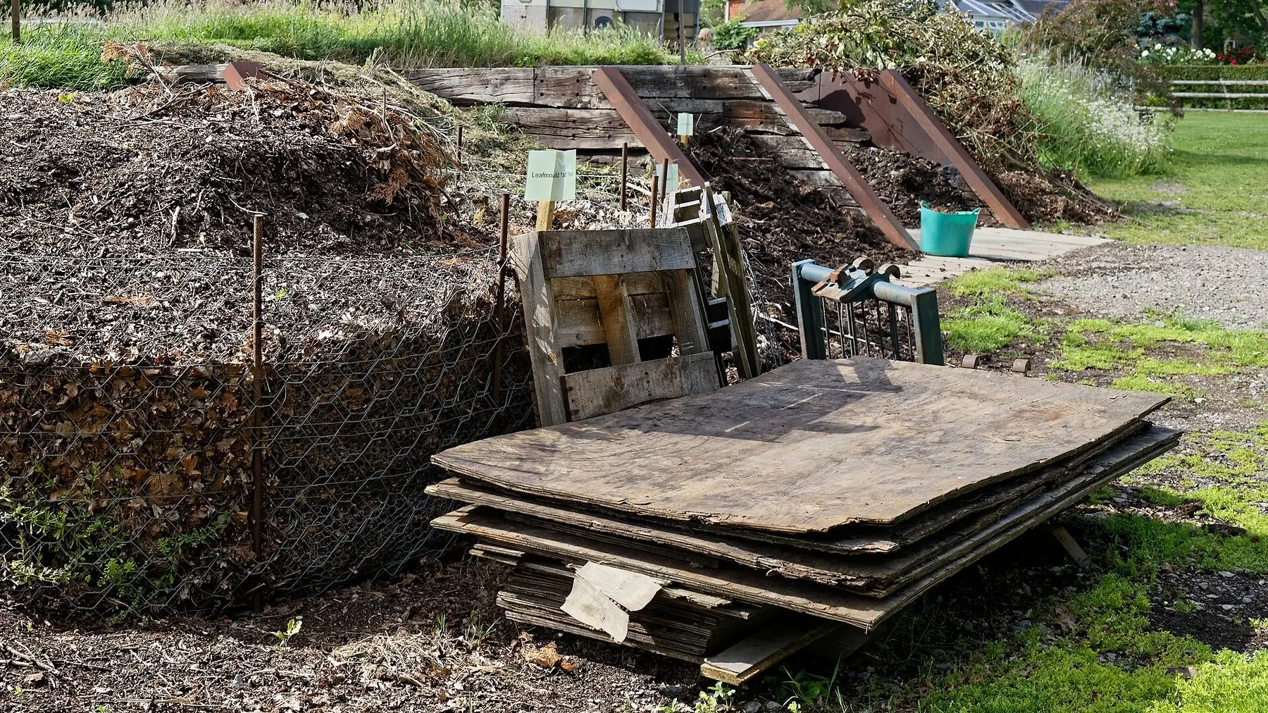A row of open-fronted timber compost bins in a garden