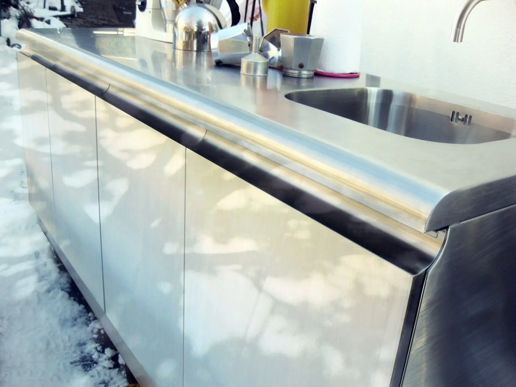 A stainless steel outdoor kitchen counter with an integrated sink