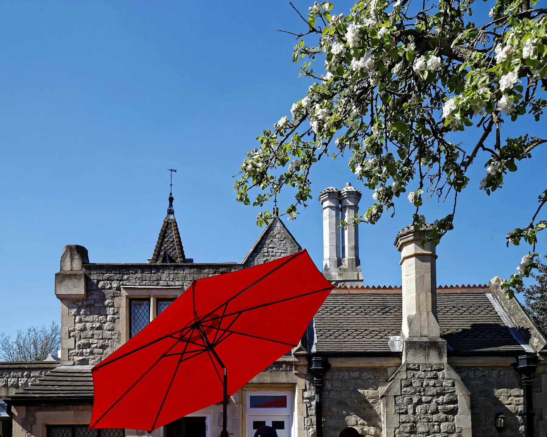A red market umbrella open over a café patio table