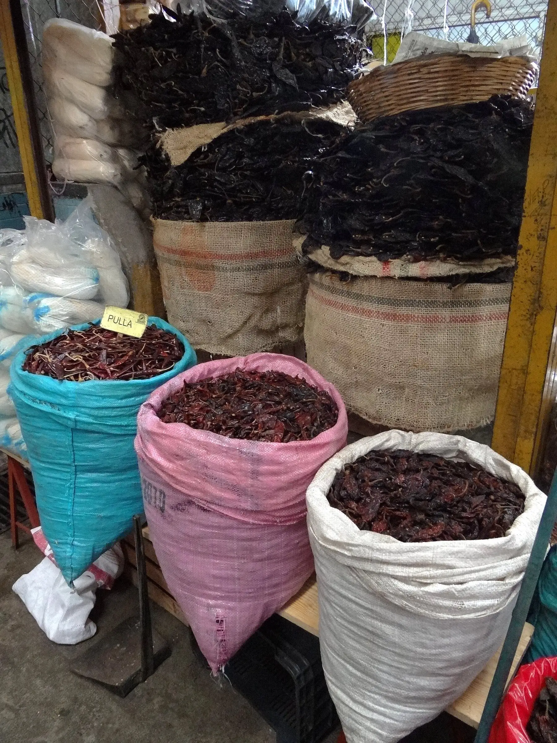 Sacks of different dried chiles side by side at a market stall in Oaxaca